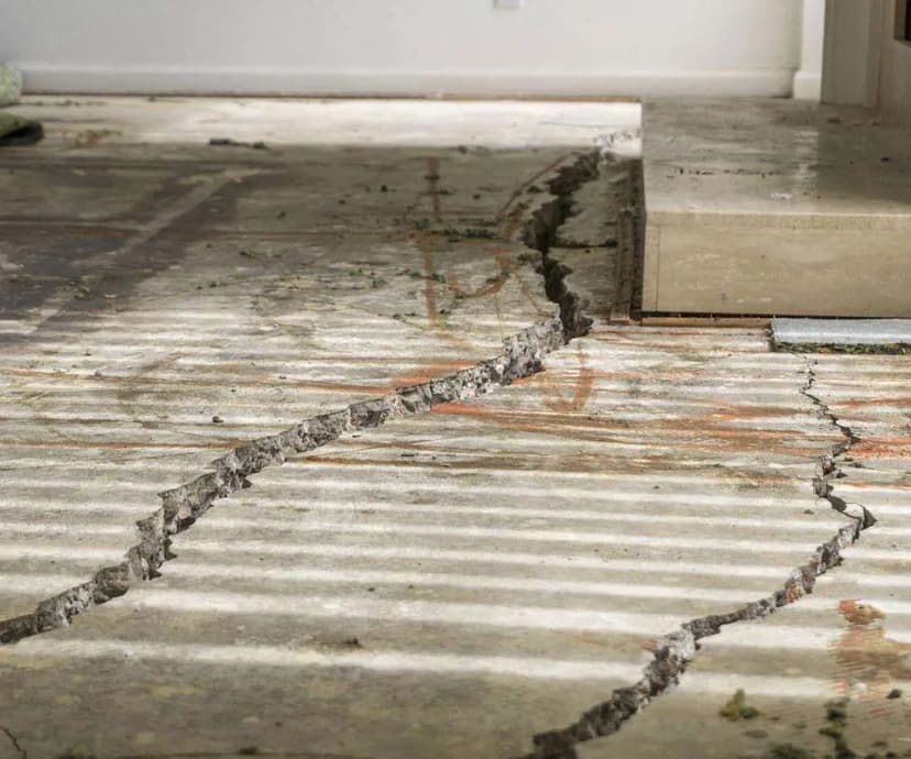 Dalinghaus Foundation Repair inspecting severe cracks and unevenness in an interior concrete slab floor.