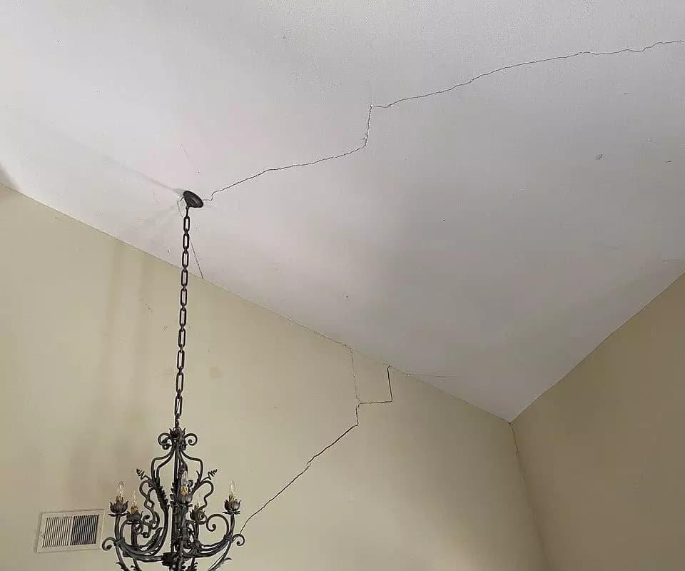 Dalinghaus Foundation Repair identifying large drywall cracks on a vaulted ceiling extending down the wall from a chandelier.