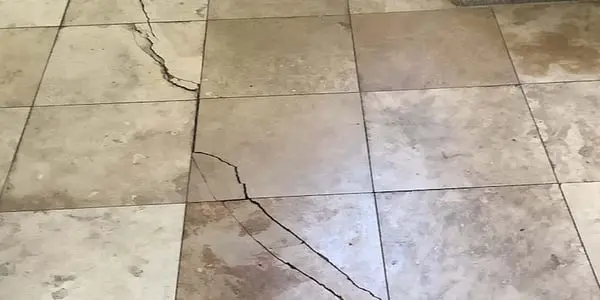 Dalinghaus Foundation Repair inspecting severe cracks in floor tiles and grout lines.