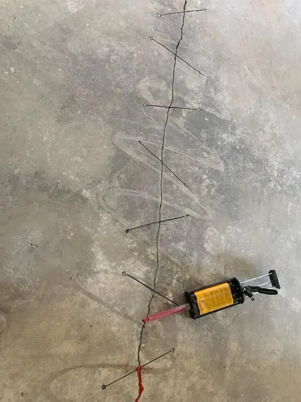 Dalinghaus Foundation Repair injecting polyurethane into a crack in a concrete slab using an injection gun with monitoring