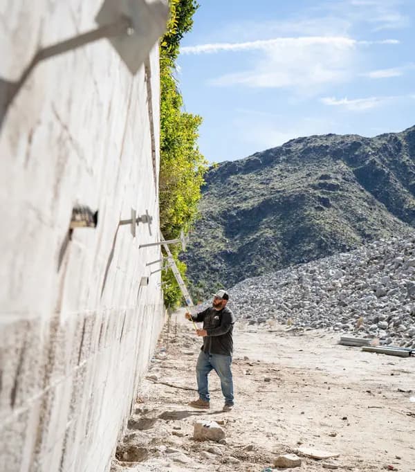 Dalinghaus Foundation Repair technician inspecting retaining wall tieback anchors on a hillside wall