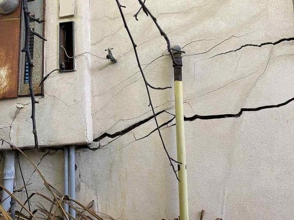 Dalinghaus Foundation Repair inspecting stucco cracking with horizontal concrete cracks in an exterior stem wall.