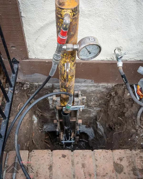 Dalinghaus Foundation Repair installing hydraulic push piers for foundation underpinning, showing equipment and pressure