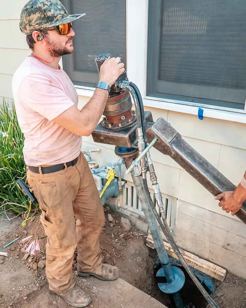 Dalinghaus Foundation Repair crew installing helical piers with a rotary drive head for foundation underpinning.