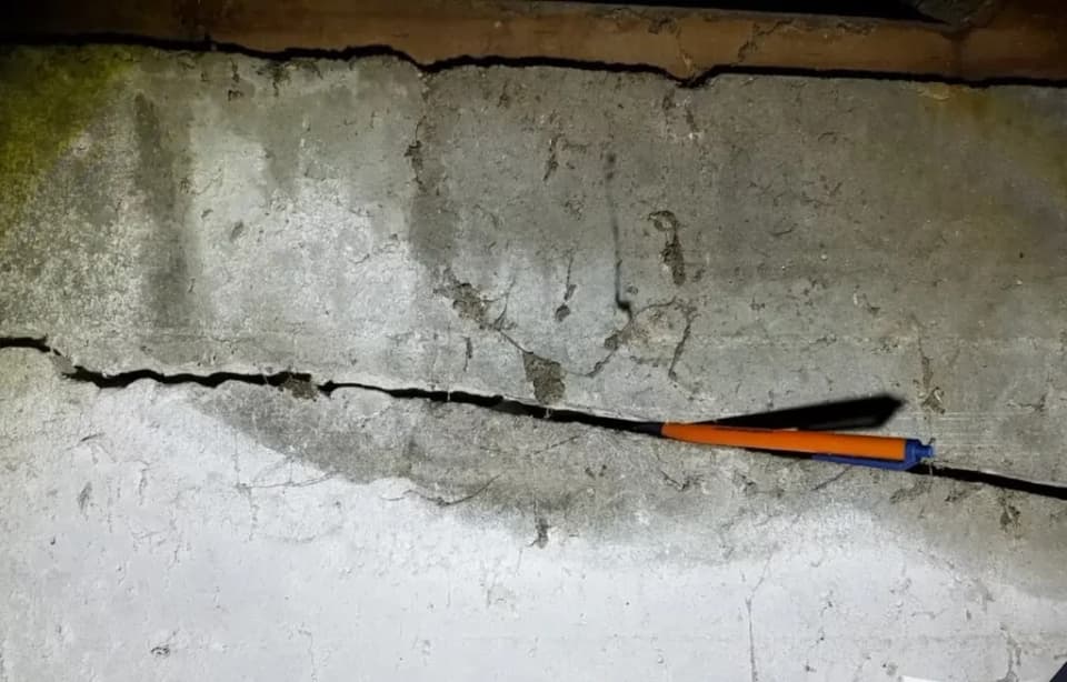 Dalinghaus Foundation Repair technician inspecting a horizontal concrete foundation crack in a crawl space.