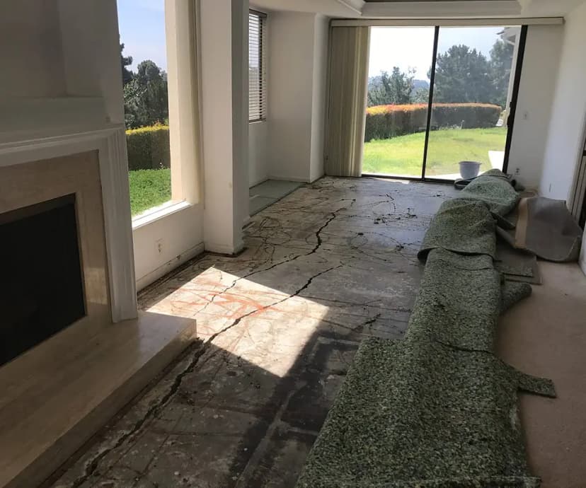 Dalinghaus Foundation Repair inspecting structural cracking in an uneven interior concrete slab foundation.