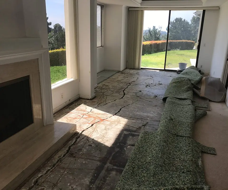 Dalinghaus Foundation Repair inspecting structural cracking in an uneven interior concrete slab foundation.