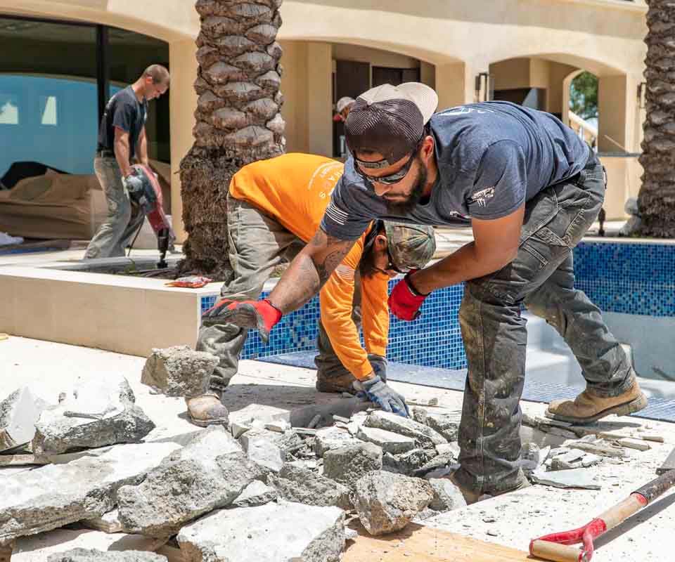 Dalinghaus Foundation Repair crew actively removing broken concrete from a pool deck area.