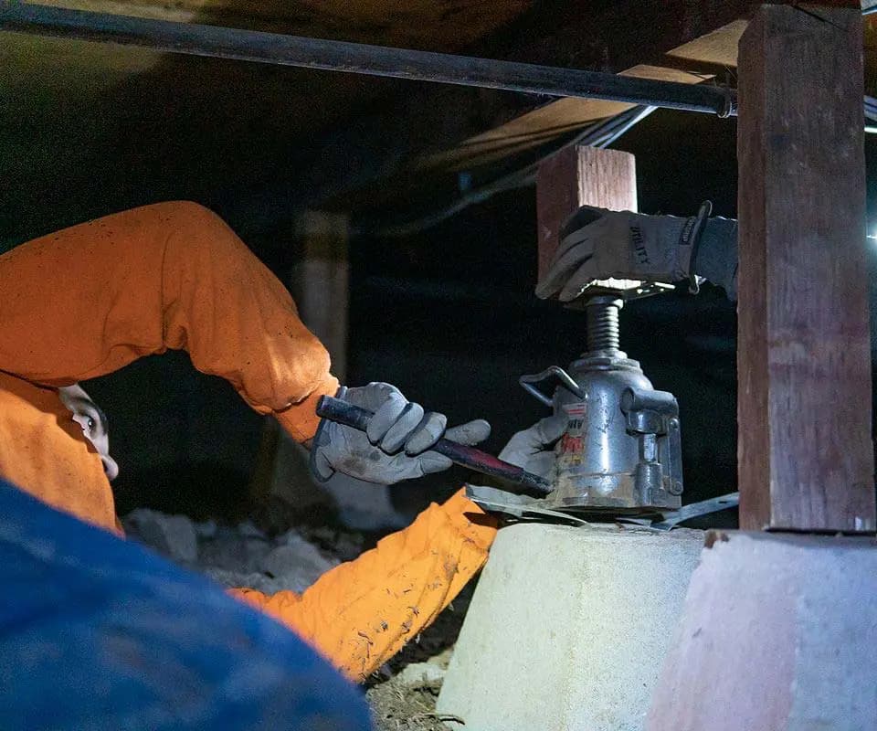Dalinghaus Foundation Repair crew installing adjustable smart jacks in a crawl space for sagging floor repair