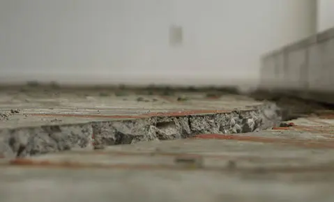 Dalinghaus Foundation Repair inspecting a significant gap between a settled concrete slab and an interior wall.