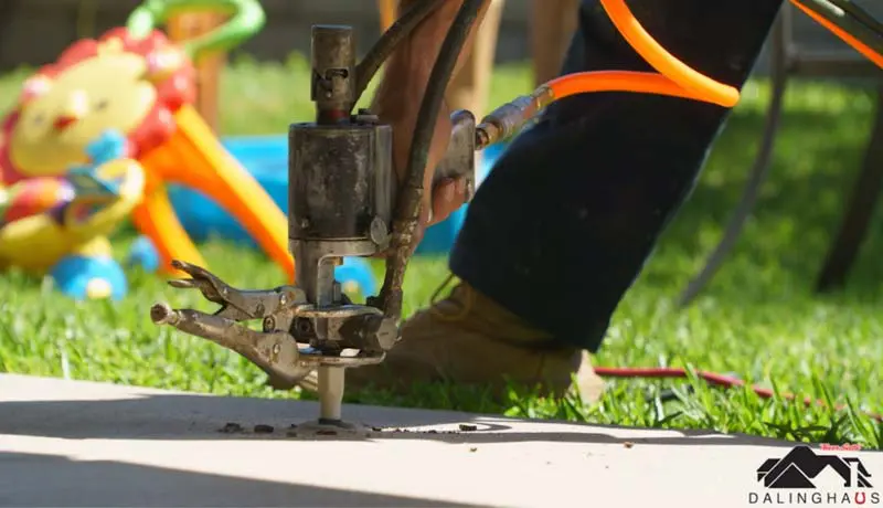 Dalinghaus Foundation Repair technician performing polyurethane foam injection for concrete leveling on an outdoor slab.