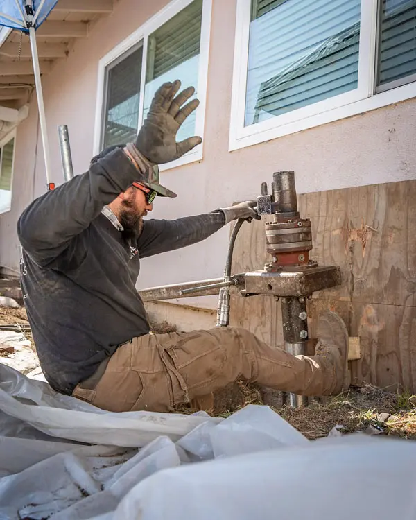 Dalinghaus Foundation Repair technician installing helical piers with a hydraulic drive head for foundation underpinning.