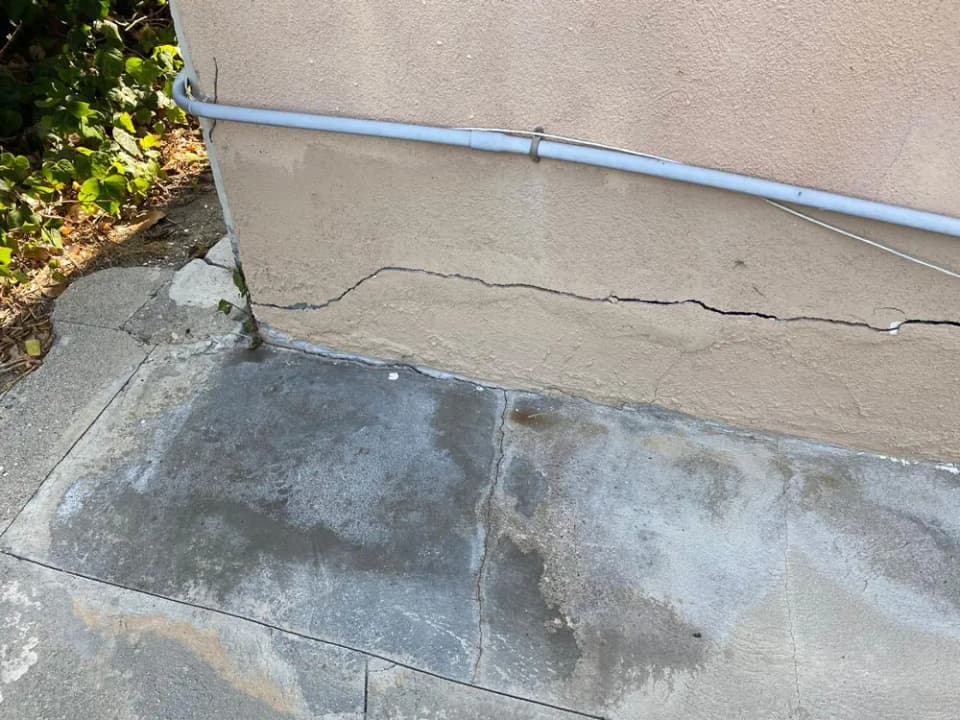 Dalinghaus Foundation Repair identifying stucco cracking and a concrete crack at an exterior slab.