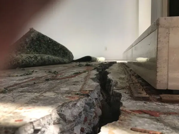 Dalinghaus Foundation Repair inspecting a wide slab crack, floor crack, and uneven concrete slab on an interior concrete