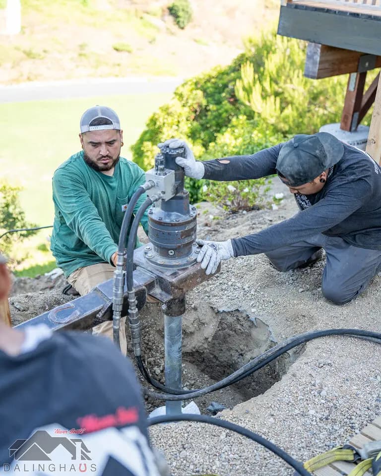 Dalinghaus Foundation Repair crew installing helical deck piers with a rotary drive head