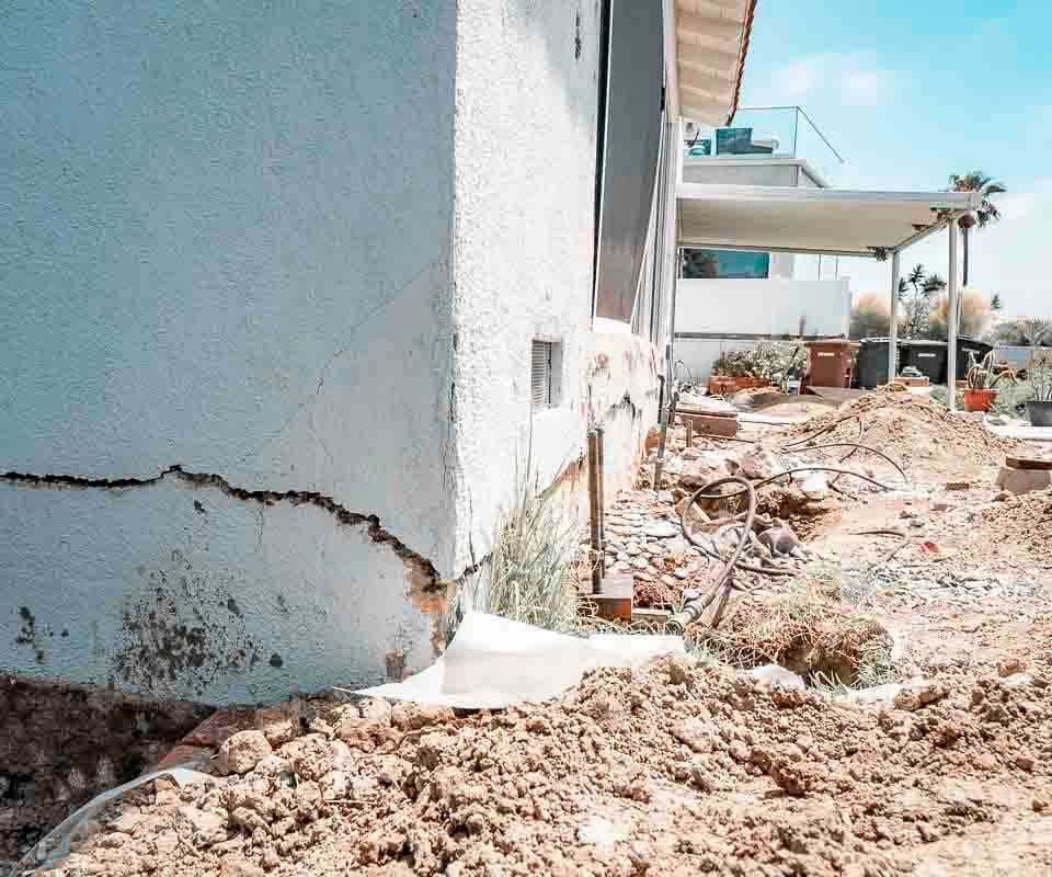 Dalinghaus Foundation Repair inspecting stucco cracking and a horizontal foundation crack with open excavation.