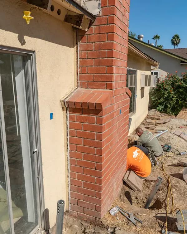 Dalinghaus Foundation Repair crew installing steel piers to stabilize a leaning chimney foundation