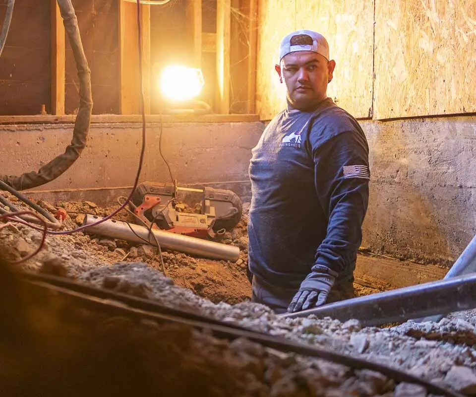 Dalinghaus Foundation Repair crew member working in an excavated crawl space, installing a foundation post.