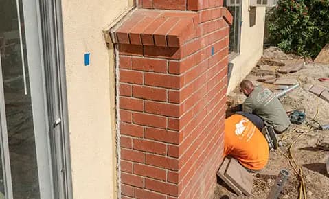 Dalinghaus Foundation Repair crew members excavating for foundation underpinning alongside a residential exterior brick