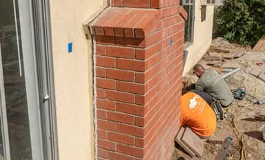Dalinghaus Foundation Repair crew members excavating for foundation underpinning alongside a residential exterior brick