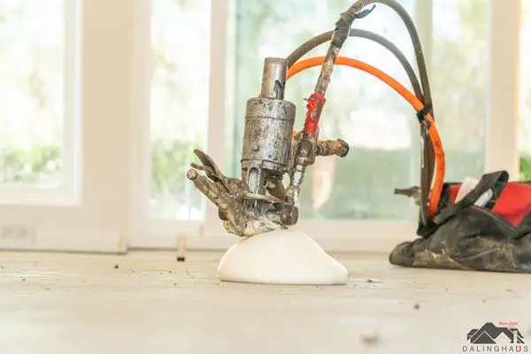 Dalinghaus Foundation Repair technician using an injection gun for polyurethane foam injection, indoors.
