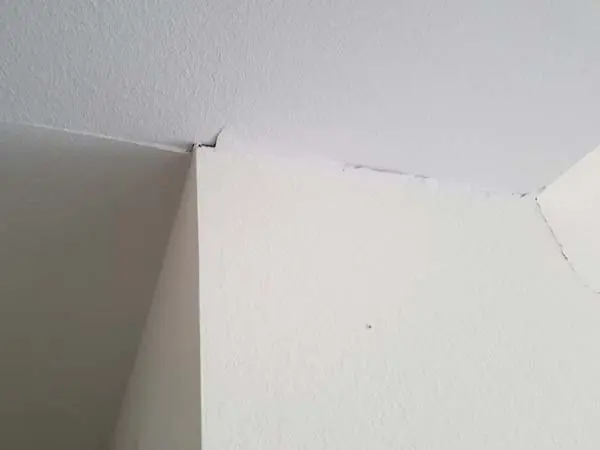 Dalinghaus Foundation Repair inspecting a prominent crack where the wall meets the ceiling, indicating potential foundation