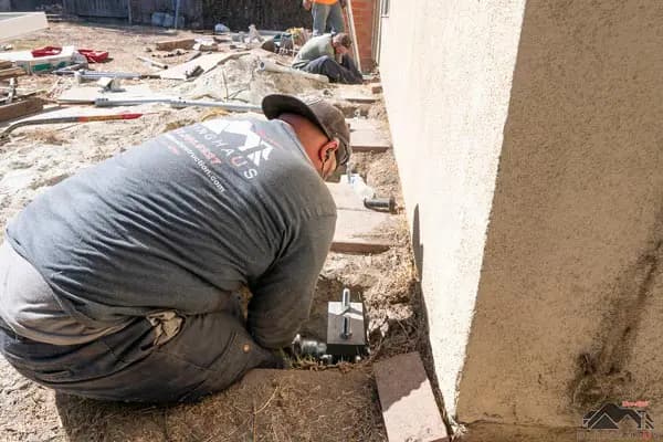 Dalinghaus Foundation Repair crew member installing steel piers for foundation underpinning in an excavated area.