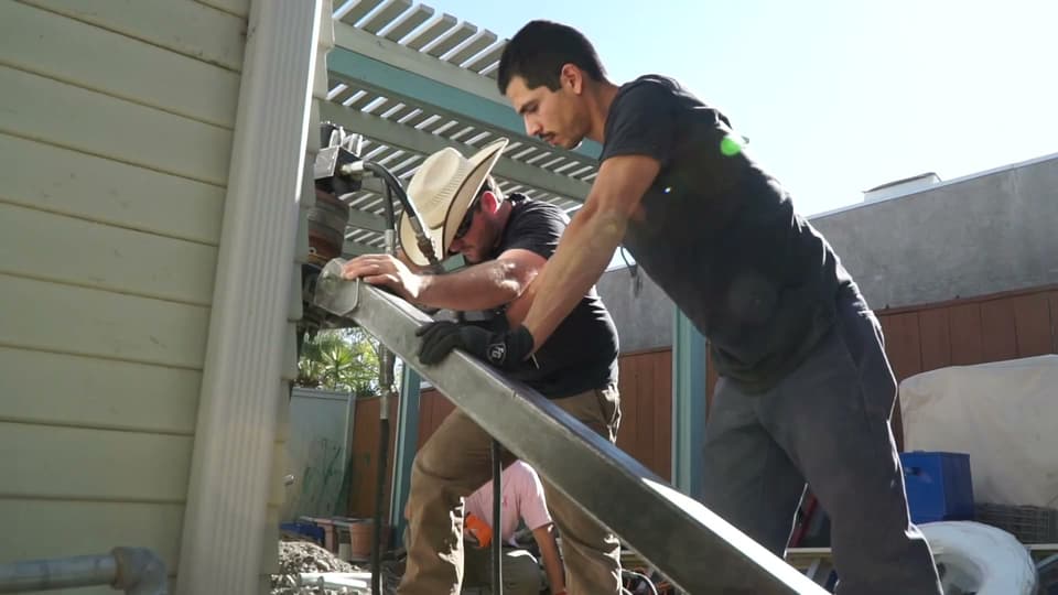 Dalinghaus Foundation Repair crew installing helical piers with a rotary drive head on a San Diego home.