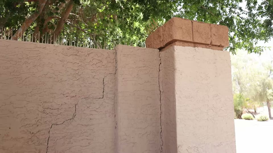 Dalinghaus Foundation Repair inspecting an exterior cracked stucco wall at a property in Arizona.