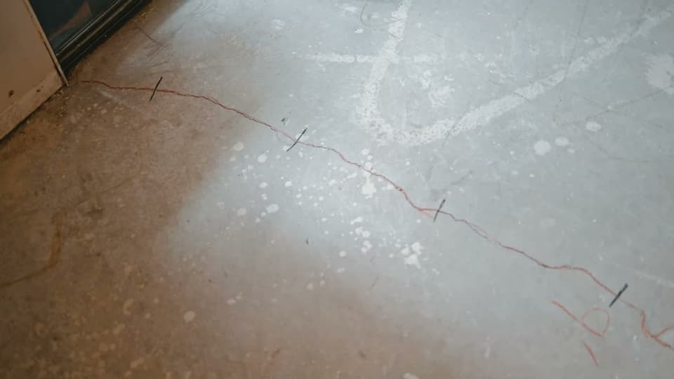 Dalinghaus Foundation Repair inspecting a long concrete slab crack on an interior floor in Laguna Niguel.