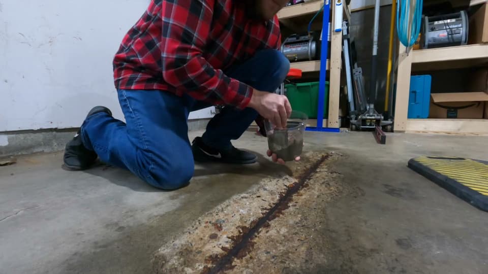 Dalinghaus Foundation Repair technician injecting polyurethane into a concrete slab crack with rusted rebar on a garage