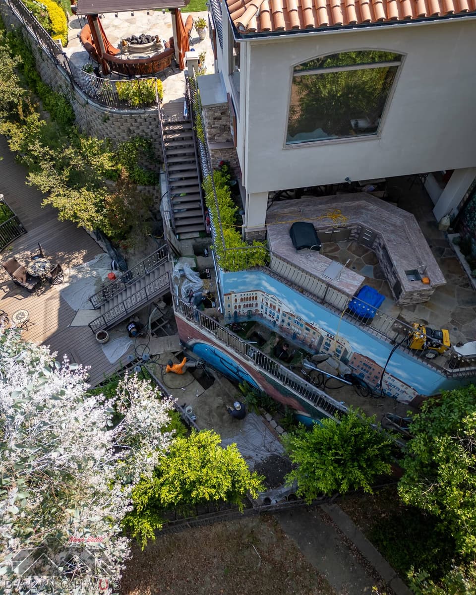 Looking down on the outdoor kitchen terrace, the painted wall and a work area with a yellow hydraulic unit.