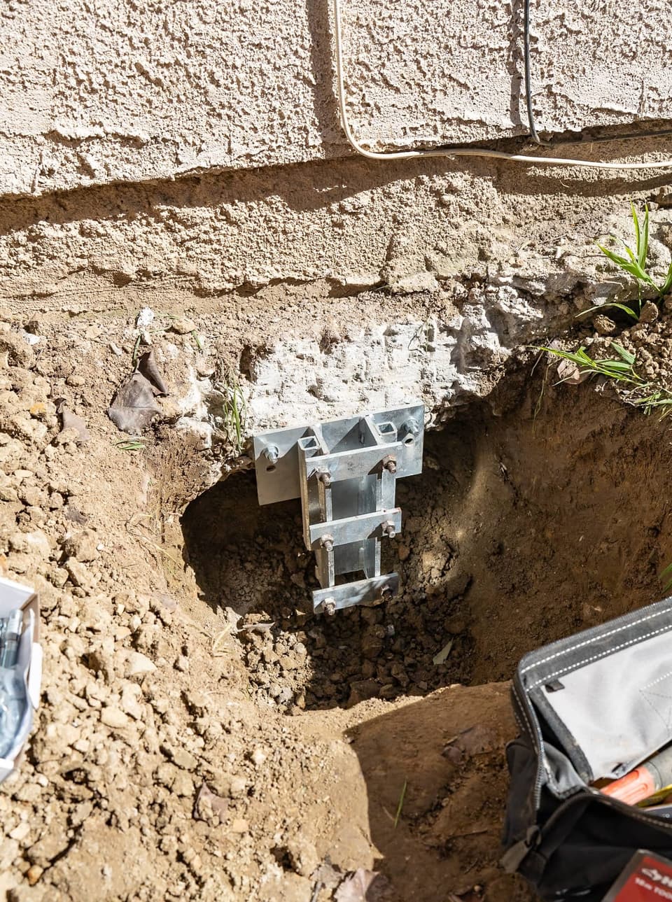 Galvanized steel bracket bolted to the prepared footing inside a freshly dug hole