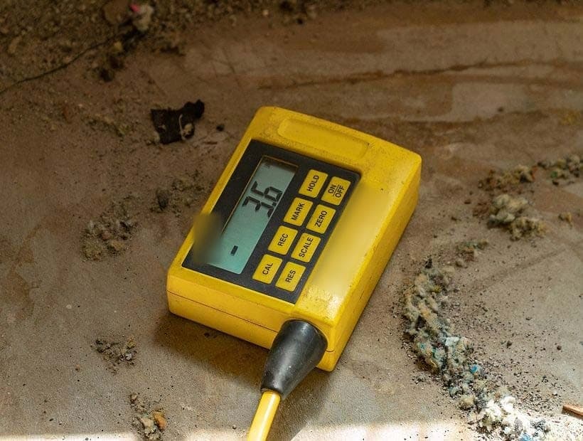 Yellow digital floor level gauge resting on a bare concrete slab