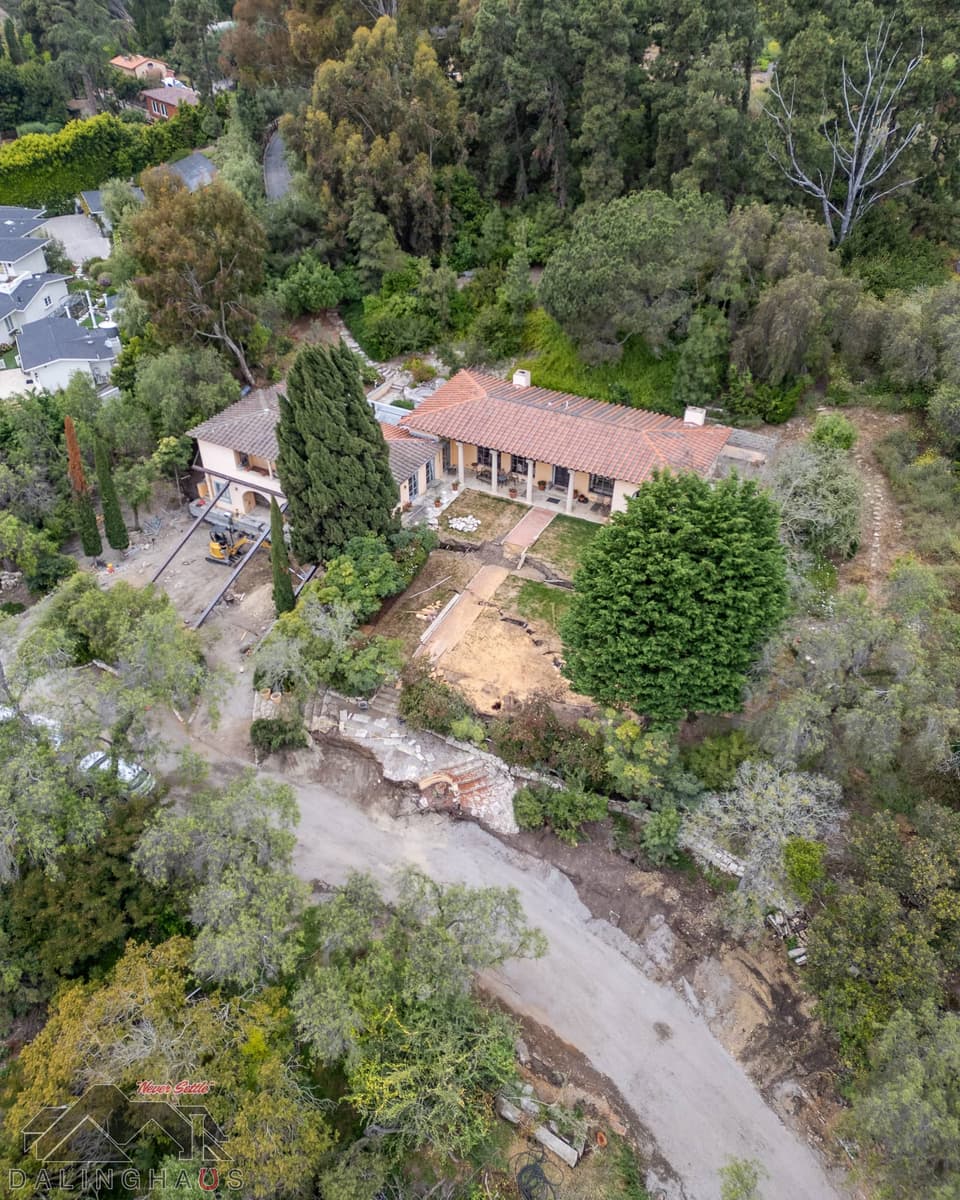 Aerial of the home and garden with an eroded dirt road and collapsed stone terrace along the lower edge