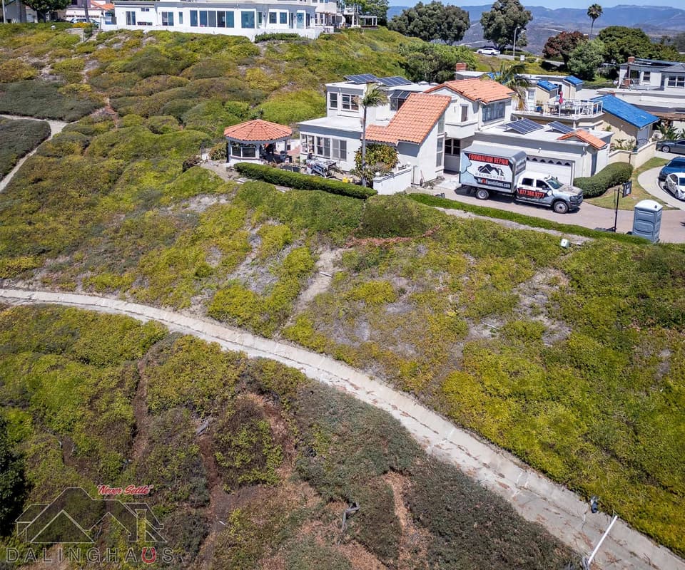 Aerial of the rear of the home from the slope side, with a company truck parked in the driveway