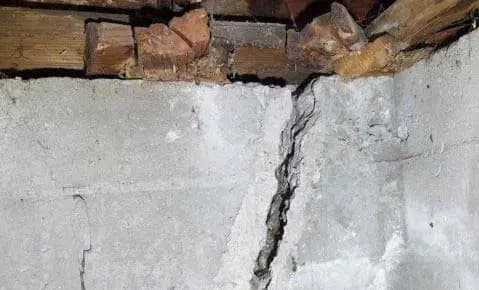 A vertical crack in a block foundation wall beneath the floor framing