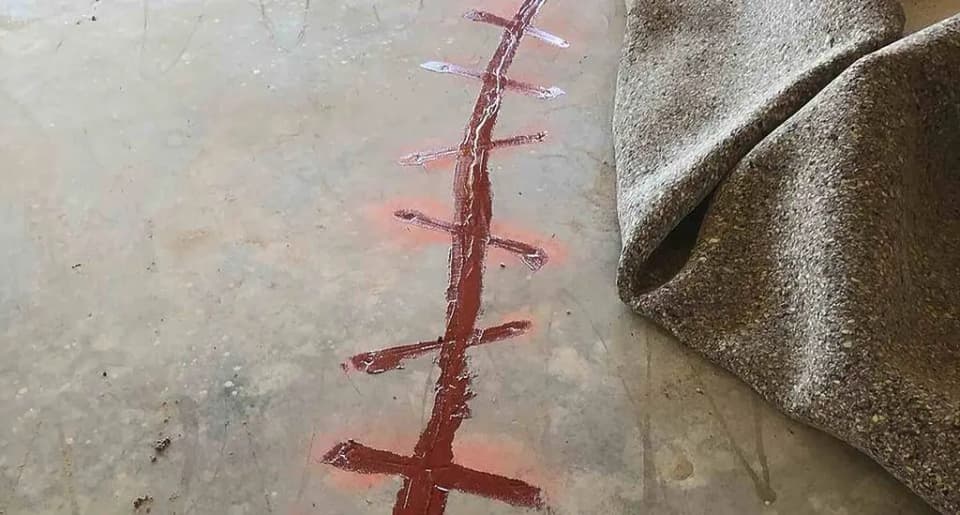Crack in an interior concrete slab, marked with red paint after the carpet was pulled back