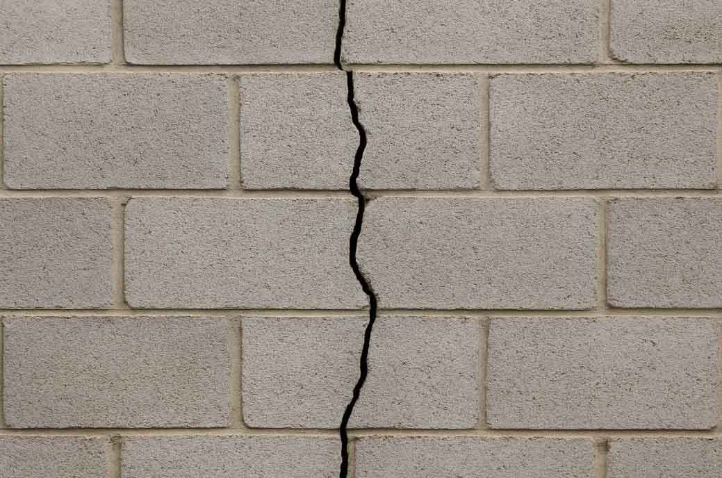 Vertical crack running straight down through the courses of a cinder block wall
