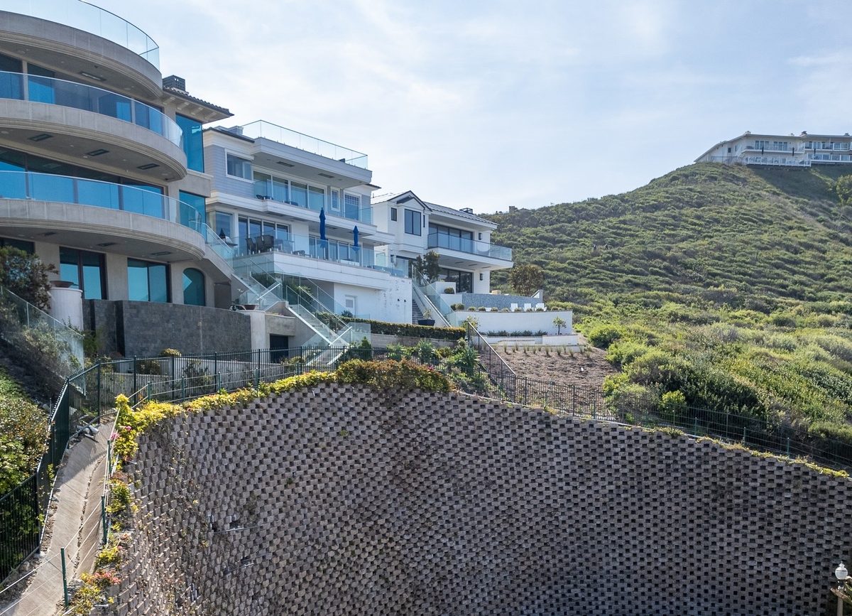 Tall block retaining wall holding back a hillside below a row of homes