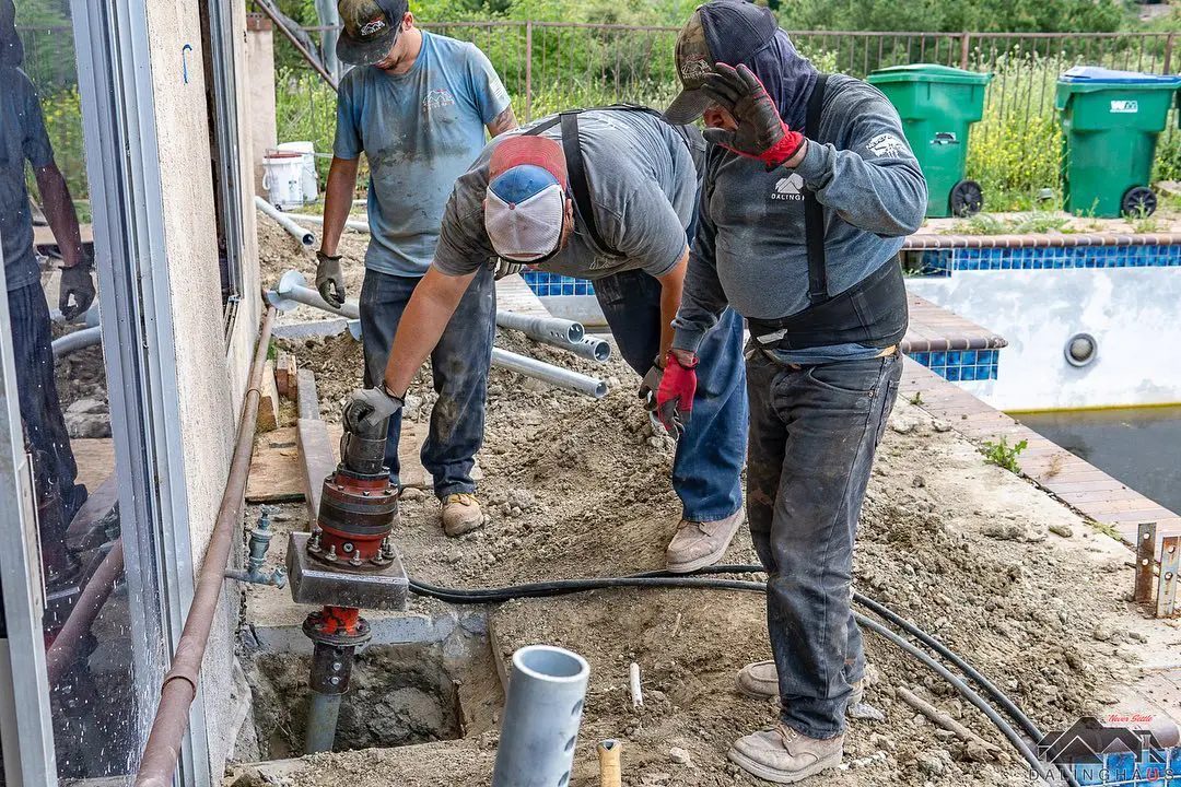 Dalinghaus crew installing a helical pier with a hydraulic drive head beside a home's foundation