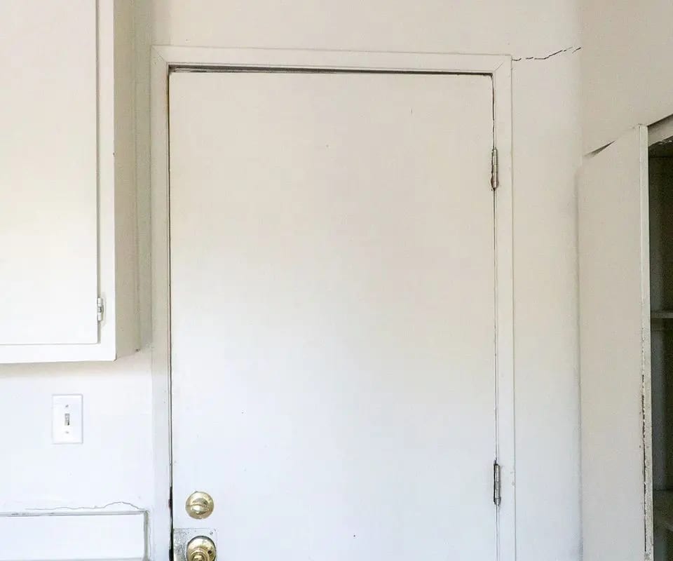 Interior door with a drywall crack running up from the top corner of the frame, a common sign of foundation settlement